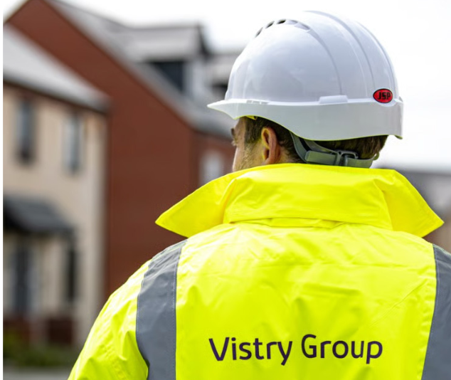 Vistry Group worker in high-visibility jacket and hard hat at a housing development.