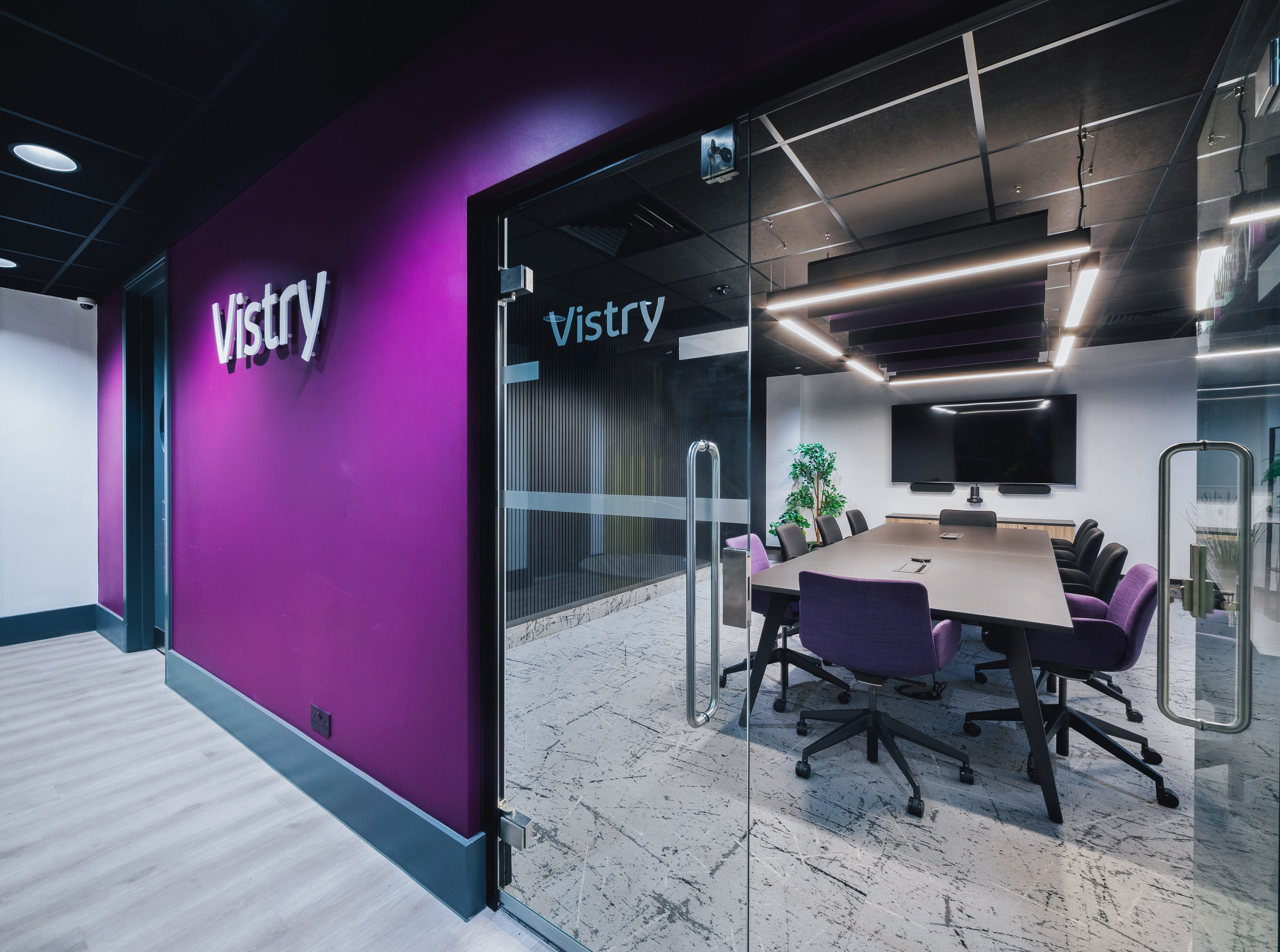 Vistry-branded meeting room with a glass entrance, purple feature wall, conference table, and modern office furnishings.